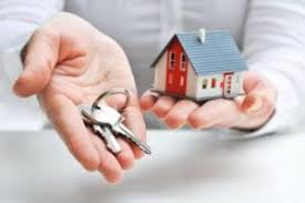 A man holding a toy house in one hand and reaching out with a set of keys in the other