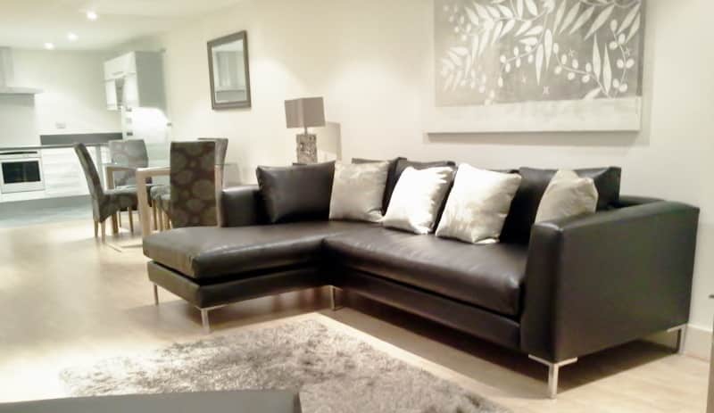A modern style apartment with a dark  leather sofa and neutral colours for the décor